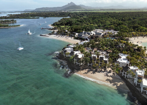 Aerial drone view of 5 star resort Shangri - La Le Touessrok with sandy beach, white villas, sailing boats and mountain range in the background, Ilot Lievres, Flacq, Mauritius.