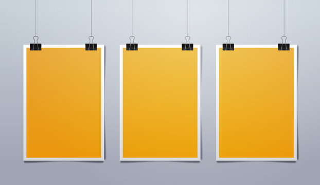 Set of three vertical yellow sheets of paper with white frame hanging on binder clips. Realistic vector illustration
