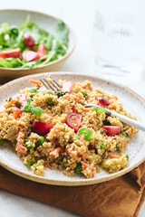 Vegan warm salad made with couscous, tomatoes, green beans, mint, roasted carrots and sweet peppers. Couscous with vegetables in bowl on light background. Variation of Tabbouleh Salad.