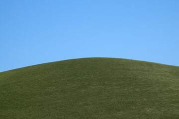 View of the artificial green hill against blue sky