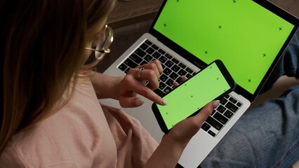 Woman using green screen smartphone with Chromakey laptop. Close-up of a woman holding a mobile...