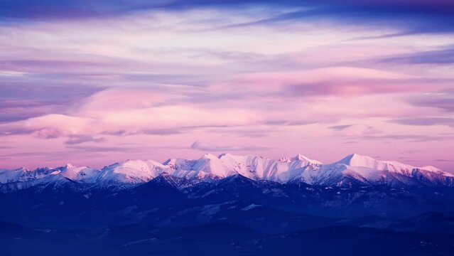 Snow-covered white mountain peaks, pink clouds at dusk, timelapse