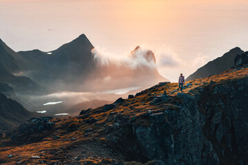 Man hiking in mountains traveling in Norway solo traveler exploring Lofoten islands outdoor active healthy lifestyle tour adventure summer vacations sustainable tourism - 741696943