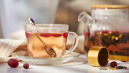 Fruits and berries tea. Glass teapot and cup on the table
