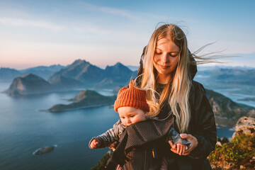 Mother hiking with baby carrier healthy lifestyle outdoor family time travel in Norway summer vacations scandinavian woman with child in mountains of Lofoten islands aerial view - 741698566