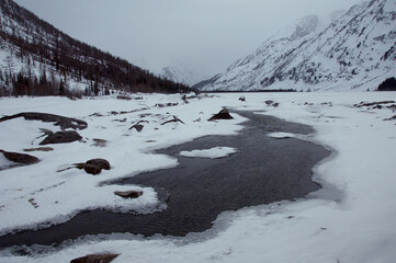 Freezing watercourse flows through snowy mountains and under polar ice cap