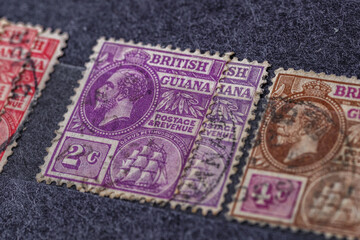 Ukraine, Kiyiv - February 3, 2024.Vintage postage stamps from British Guiana.Collection  vintageof stamps and magnifying glass.Postage stamps from different countries and times