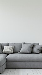 A gray fabric sofa with white pillows and a gray throw blanket in a living room with white walls and wood floors