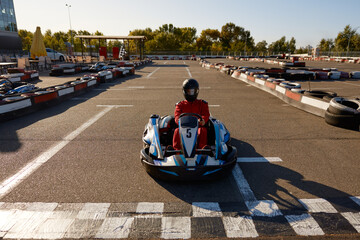 Competitive man racing in go-carts at finish of motor race track
