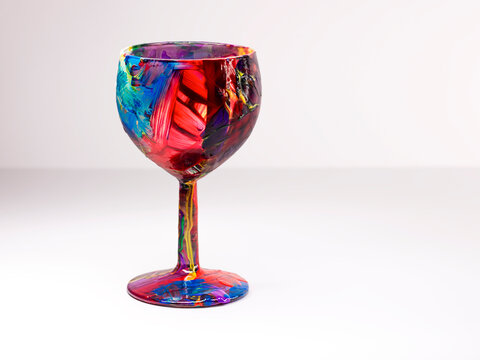 Single wine glass painted with multi coloured acrylic paint