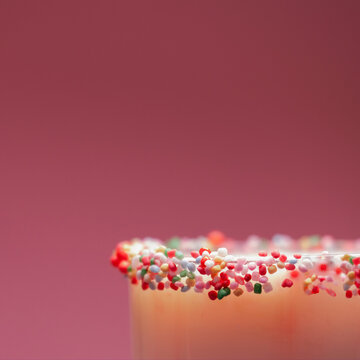 Close-up of a cocktail in a glass with a sugared rim of multi coloured hundreds and thousands