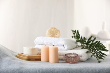 Fototapeta na wymiar Spa composition. Burning candles, soap, towels and loofah on soft grey surface