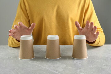 Man playing shell game at light marble table, closeup
