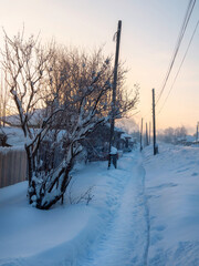 Frozen winter village, a trail through snowdrifts