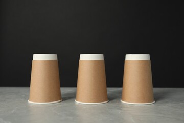 Shell game. Three paper cups on grey marble table