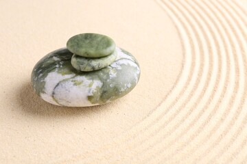 Fototapeta na wymiar Zen garden stones on beige sand with pattern. Space for text