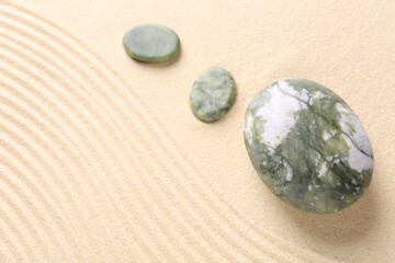 Zen garden stones on beige sand with pattern, above view. Space for text
