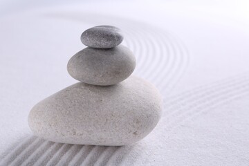 Fototapeta na wymiar Zen garden stones on white sand with pattern, closeup