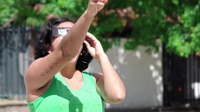 Smiling young latin woman watching an eclipse of the sun with eclipse glasses
