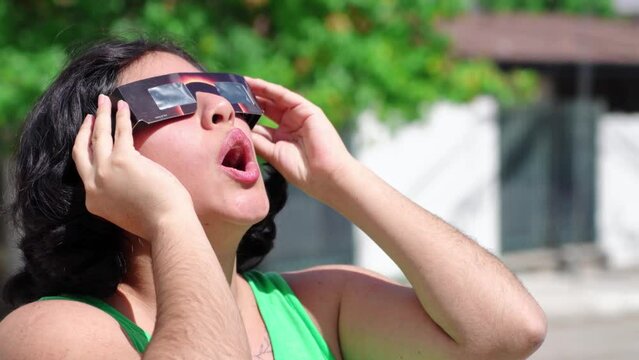 Happy young latina woman with solar eclipse glasses, watching a solar eclipse