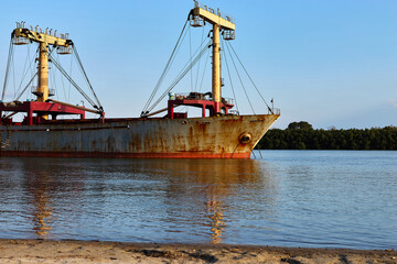 Naklejka premium The bow of the old rusty cargo ship in Danube river at anchor near the shore