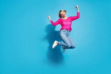 Full length photo of lovely young lady jump raise fists win lottery dressed stylish pink knitted...