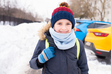 portrait of an 11 year old boy in dark clothes who goes to school on a winter snowy day.