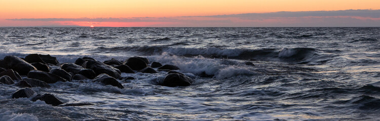 breakwater with surf at sunset.