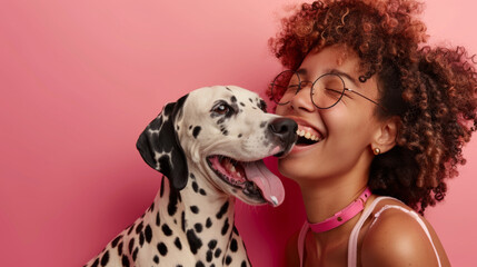 A joyful woman in sunglasses receives a loving lick on the face from a playful Dalmatian against a radiant red background, showcasing their affectionate bond.