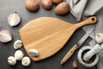 Flat lay composition with wooden cutting board and products on dark textured table