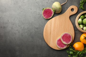 Flat lay composition with wooden cutting board and products on dark textured table. Space for text