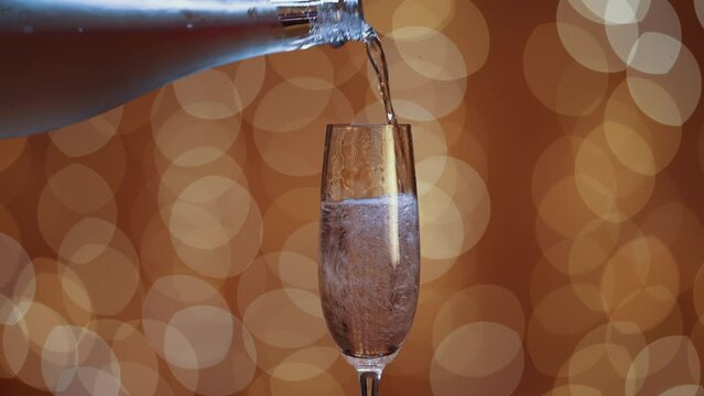 botella de champan llena una copa. efecto bokeh de luces doradas en el fondo. 
