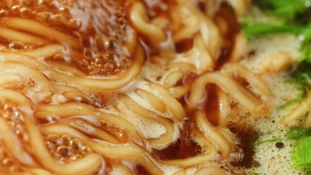 Cooking instant noodles in boiling water with spices close-up. Asian fast food. Instant noodles, or instant ramen, is a type of food consisting of noodles sold in a precooked and dried block with