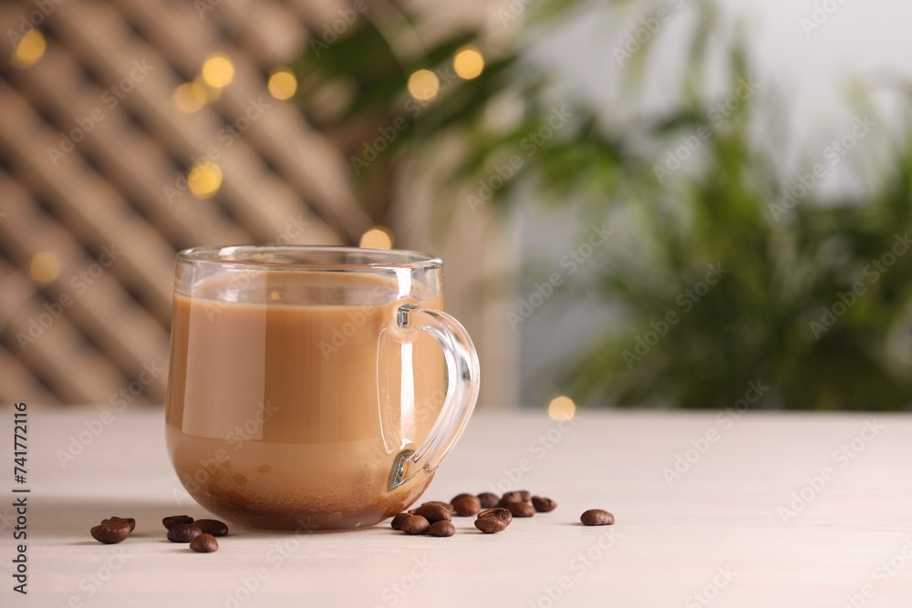 Sticker Delicious coffee with milk in cup and beans on white wooden table, closeup. Space for text