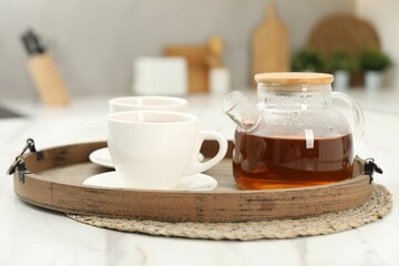 Aromatic tea in glass teapot and cups on white table