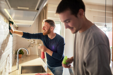 Gay couple cleaning modern kitchen at home