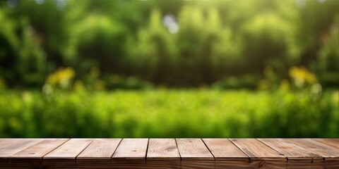 Wooden table display with green grass background and blurred foliage. - obrazy, fototapety, plakaty