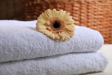 Stacked terry towels and flower on white table, closeup