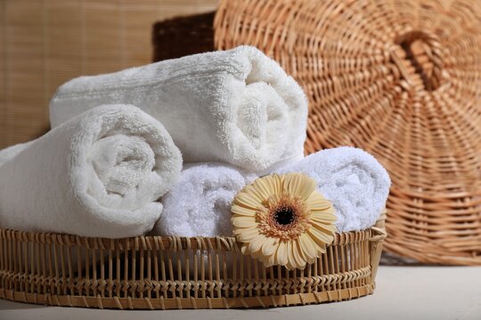 Rolled terry towels and flower on white table indoors