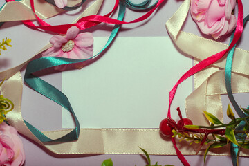 Frame made of ribbons and flowers on a white background with copy space. Celebration decoration creative concept. 