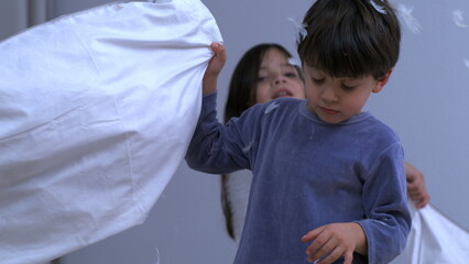 Little boy defending himself with pillow from sister amidst in pillow battle captured in slow motion