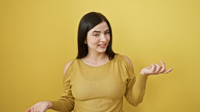 Young beautiful hispanic woman standing clueless and confused expression. doubt concept. over isolated yellow background