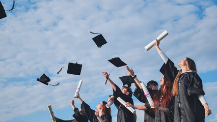 Happy college graduates tossing their caps up at sunset.