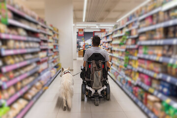 Man with disability and his service dog shopping in market store using electric wheelchair