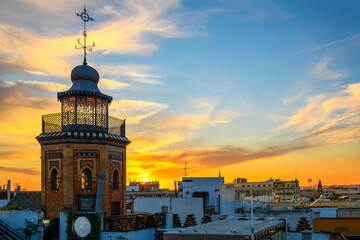 Rooftop view as the sun sets behind the Secret Tower of Espiau, or La Torre secreta de Espiau, in the central Barrio Santa Cruz district of Seville, Spain.