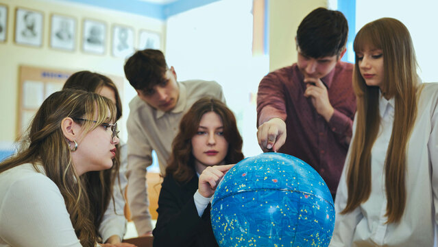 Students look at a globe of the starry sky in a classroom at school.