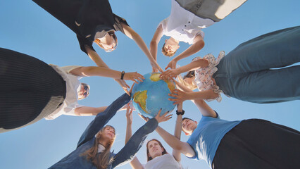 Friends holding a geographical globe in their hands. The concept of keeping the world safe.