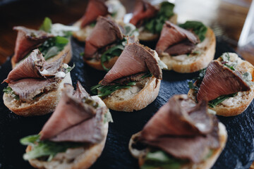 Beautifully decorated catering banquet table with different food snacks and appetizers with sandwich, caviar, fresh fruits on corporate christmas birthday party event or wedding celebration.