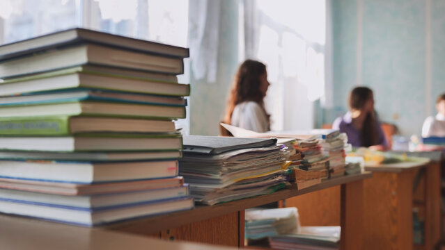 Stacks of books and notebooks in a school classroom during recess.