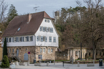 Historisches Pfarrhaus mit Walmdach, Sandsteinsockel, Sprossenfenstern und Fensterladen mit Kirchhofmauer und Kirchturm auf Anhöhe